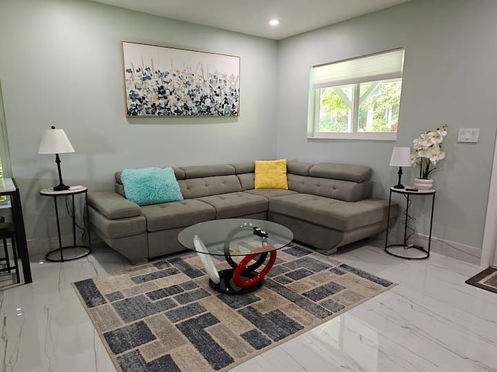 მოიწყვეთ კომფორტული დასვენება ღია მისაღებ ოთახში, რომელშიც არის 75‑დუიმიანი სმარტ‑ტელევიზორი