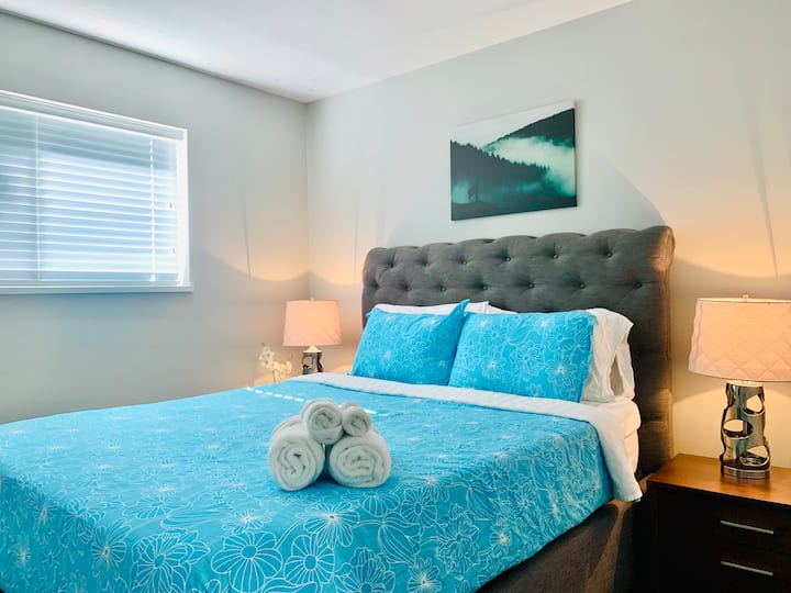 Ამ საძინებელში არის საწოლი Queen, რომელშიც არის ორი გვერდითი მაგიდა, ორი ლამპა და კარადა საკიდებით.