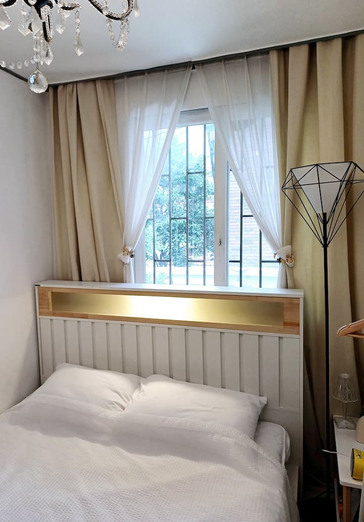 Ich kann einen Baum durch das kleine Schlafzimmerfenster sehen. Wir stellen ein Bett mit einem hohen Kopfteil auf, um das Gefühl eines offenen Kopfteils zu reduzieren und dir einen guten Schlaf zu ermöglichen. 