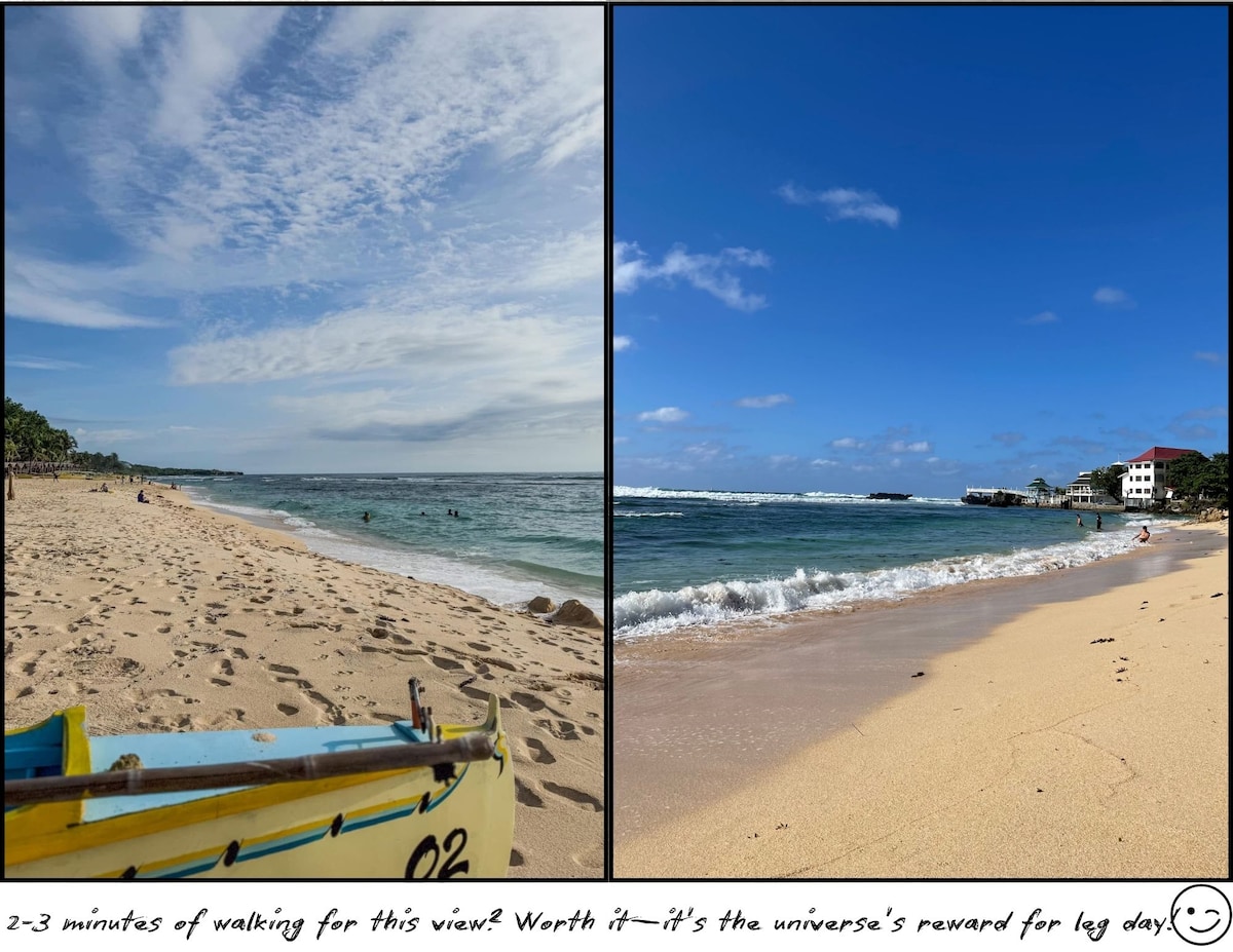 A sandy beach is captured, featuring gentle waves rolling onto the shore. Footprints are visible in the sand, and a small boat rests nearby. The clear blue sky is adorned with fluffy white clouds, while a distant shoreline showcases a mix of greenery and buildings.