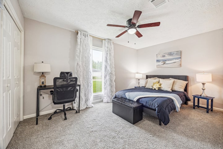 Amplio segundo dormitorio con un relajante tema costero, con un escritorio y una silla para un cómodo espacio de trabajo. Hay una cómoda escondida dentro del armario para un almacenamiento adicional, y las persianas opacas garantizan una noche de sueño reparador.