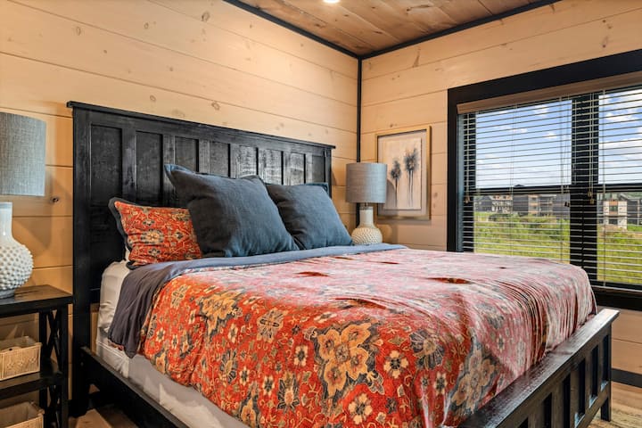 Cozy wood-paneled bedroom with bold bedding and bright natural light