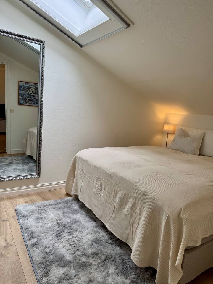 ห้องนอนสบายๆ มีหน้าต่างระบายอากาศพร้อมม่านบังแสงและตาข่ายกันแมลง กระจกขนาดใหญ่และตู้เสื้อผ้า 