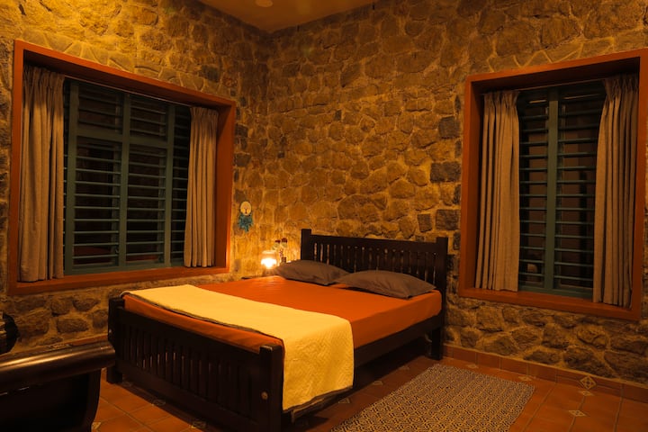 Një dhomë gjumi rustike me mure guri, një krevat dopio "queen" dhe thekse druri. Dritaret e mëdha me grila jeshile ofrojnë pamje nga plantacionet. Ndriçimi i butë krijon një pushim të rehatshëm dhe të qetë.