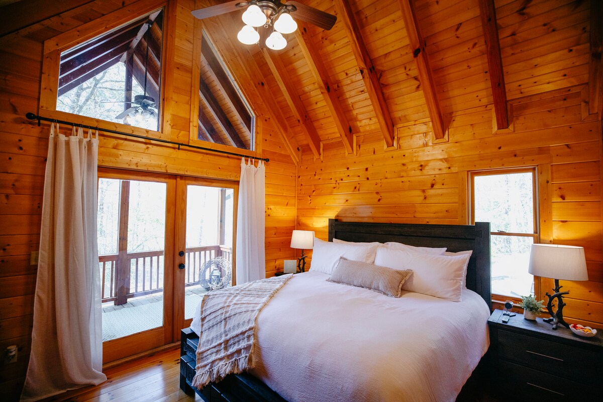 Пространа главна спална соба со брачен кревет (широк 150-179 см), сводести тавани, сопствена бања и пристап до приватен поплочен двор со столови за лулање. Удобно, светло и совршено за мирен одмор во шумата.