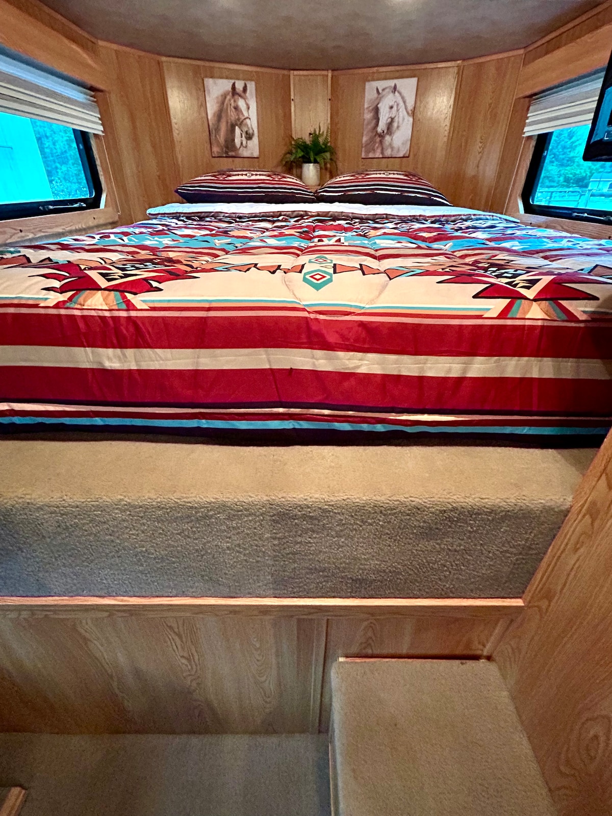 Het queensize bed ligt in de 'loft'-ruimte van je gooseneck-trailer. 