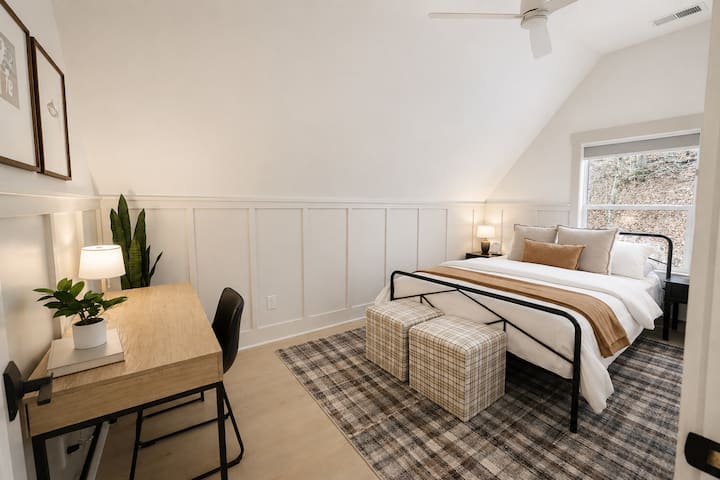This cozy bedroom features a queen bed, vaulted ceilings, comfortable bedding, blackout shades, and a dedicated workspace.