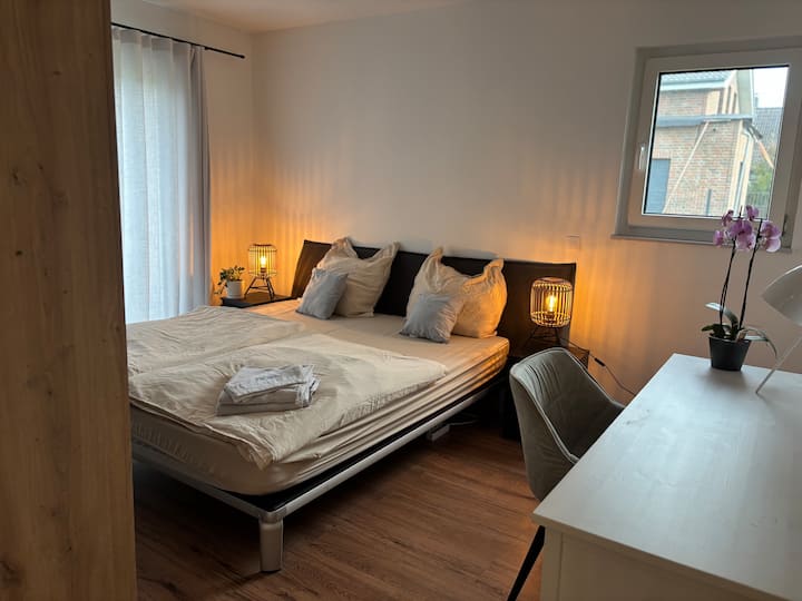 Светла спална соба со удобен брачен кревет, пријатни светла и мал простор за работа. Свежите крпи и деталите со љубов создаваат пријатна атмосфера.
