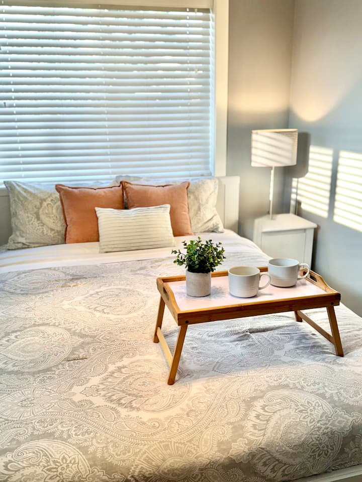 Chambre lumineuse et accueillante avec un lit queen, des draps propres, deux fenêtres ensoleillées et une télévision pour des soirées relaxantes.