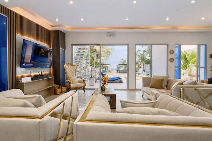 Sala de estar con vistas al mar, perfecta para relajarse y socializar. Cuenta con amplios sofás, una televisión inteligente y la opción de karaoke bajo petición, lo que te permite disfrutar de momentos únicos de diversión con tu grupo.