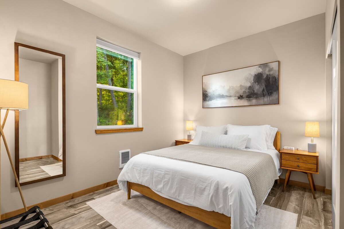 Chambre avec éclairage d'ambiance sous le lit, vue sur les arbres et ventilateur de plancher.