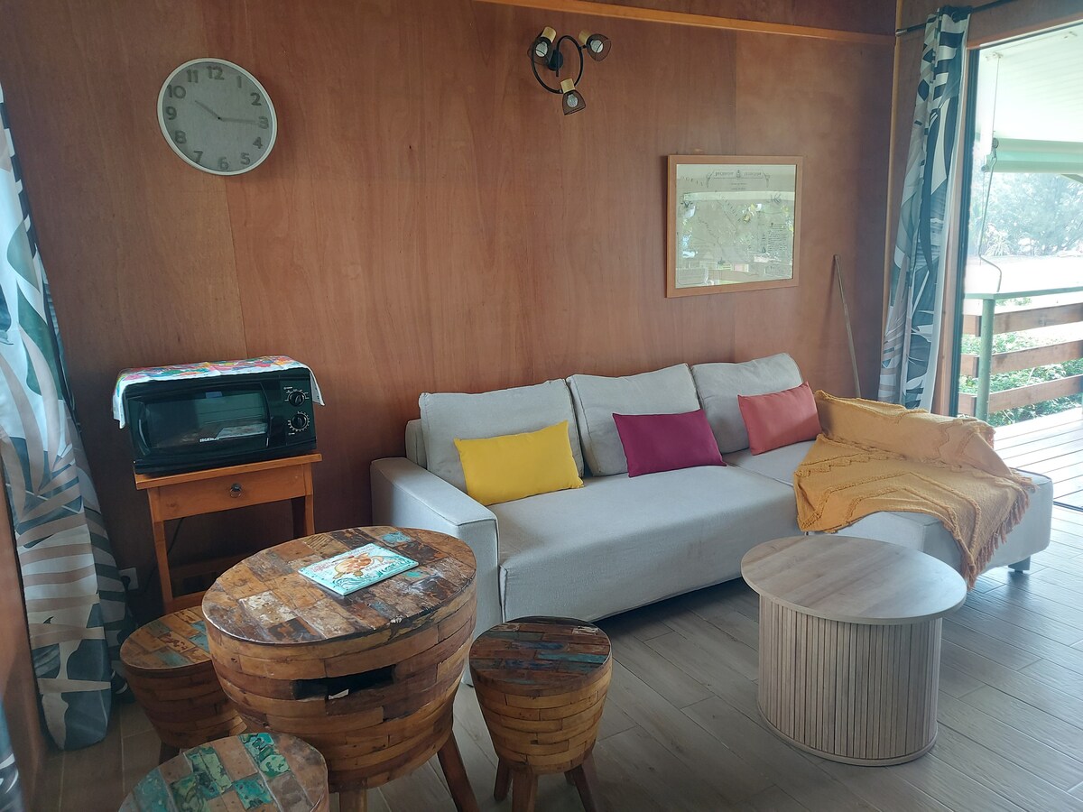 дневна соба со кауч (на спуштање) со тркалезна масичка за кафе, мала маса за играње или појадок пред долината Пунаруу и микробранова печка 