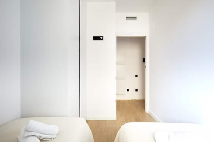 Chumba kimoja cha kulala chenye starehe kilicho na kitanda kimoja, meza ya kando ya kitanda na taa ya kusomea. Tani zisizoegemea upande wowote, mapambo ya mbao na makabati yaliyojengwa ndani huunda sehemu angavu, ya kisasa yenye dirisha linaloingiza mwanga wa asili.