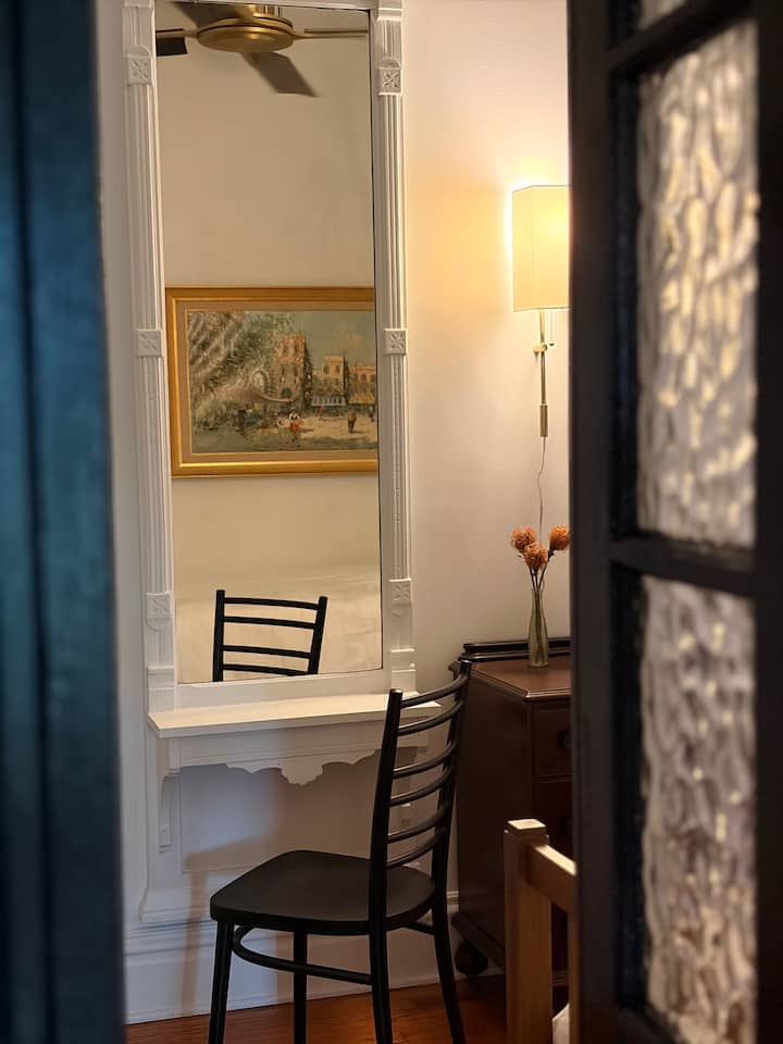 Enter through the original french doors to secondary bedroom. The antique pier mirror make a charming dressing station.
