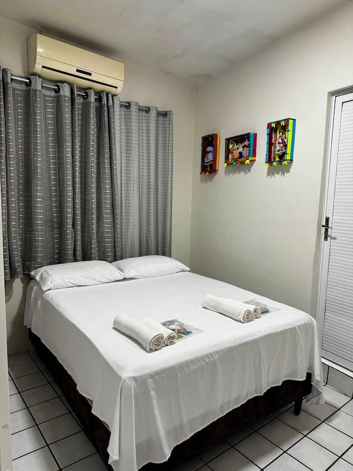 ¡Esta es nuestra suite! Tiene una cama doble, un armario, aire acondicionado, cortina opaca y el baño. ¡Tu lugar de descanso! Tenemos un hermoso y funcional kit de higiene, así como ropa de cama, almohadas y toallas. 