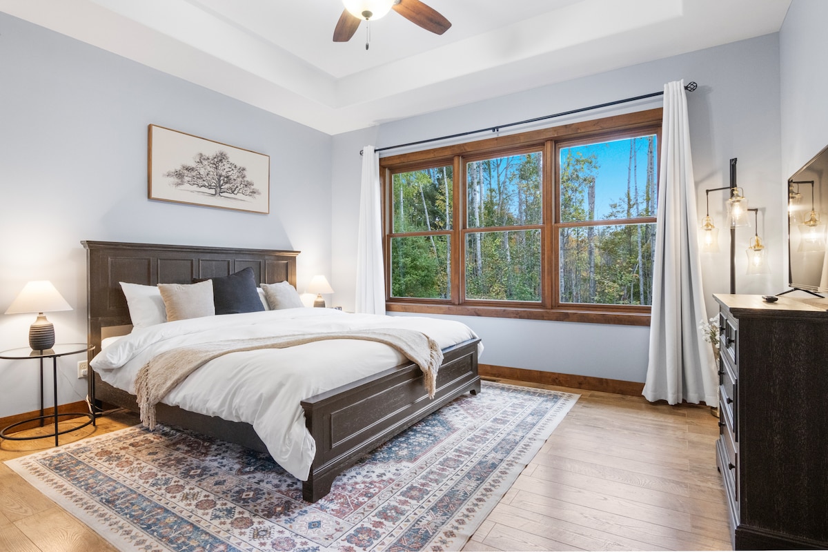 Chumba cha kulala cha Msingi kina mapambo mazuri, mandhari nzuri ya Mto na mazingira ya asili, runinga, kituo cha kuchaji simu, godoro la kifahari, Bafu la kujitegemea la En Suite lenye beseni la jakuzi na bafu la kuingia, kabati la matembezi lenye hifadhi nyingi na kitanda cha mtoto kinachobebeka.