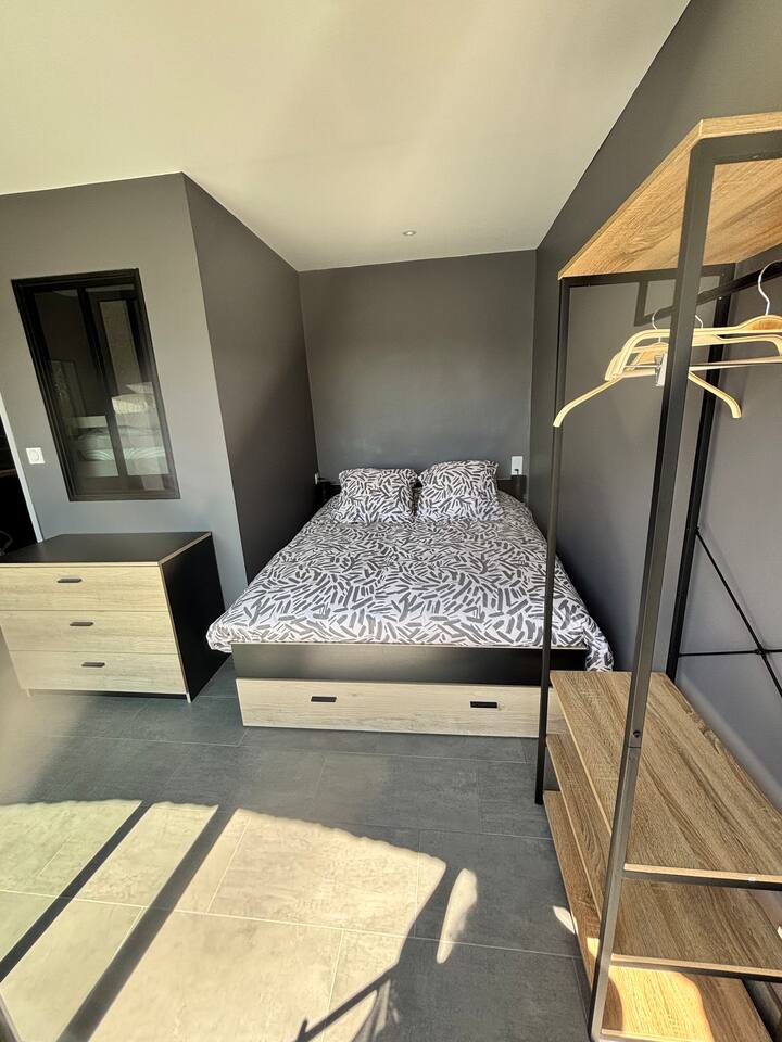 Spálňa s posteľou 140 x 200 cm, komoda, šatníková skriňa s veľkým skleneným oknom s výhľadom na balkón s výhľadom na záhrady a bazén.