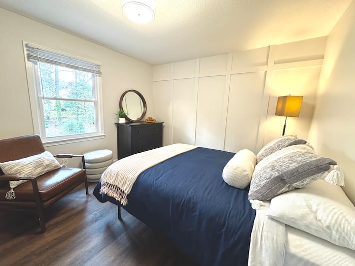 Relájate en el dormitorio principal con vistas privadas arboladas, cama tamaño queen, baño completo con ducha, acogedora silla de lectura y TV para tu entretenimiento.