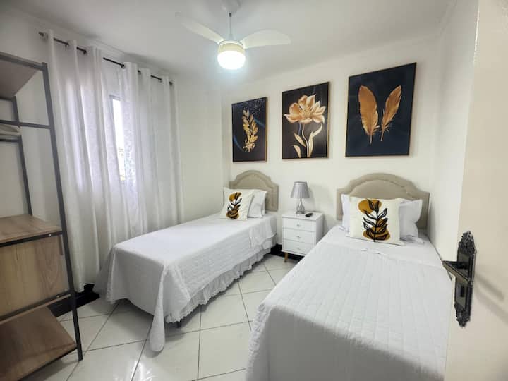 Bedroom equipped with 2 single beds, a smart TV, a ceiling fan, and space to store clothes, bedding, blankets and spare pillows.