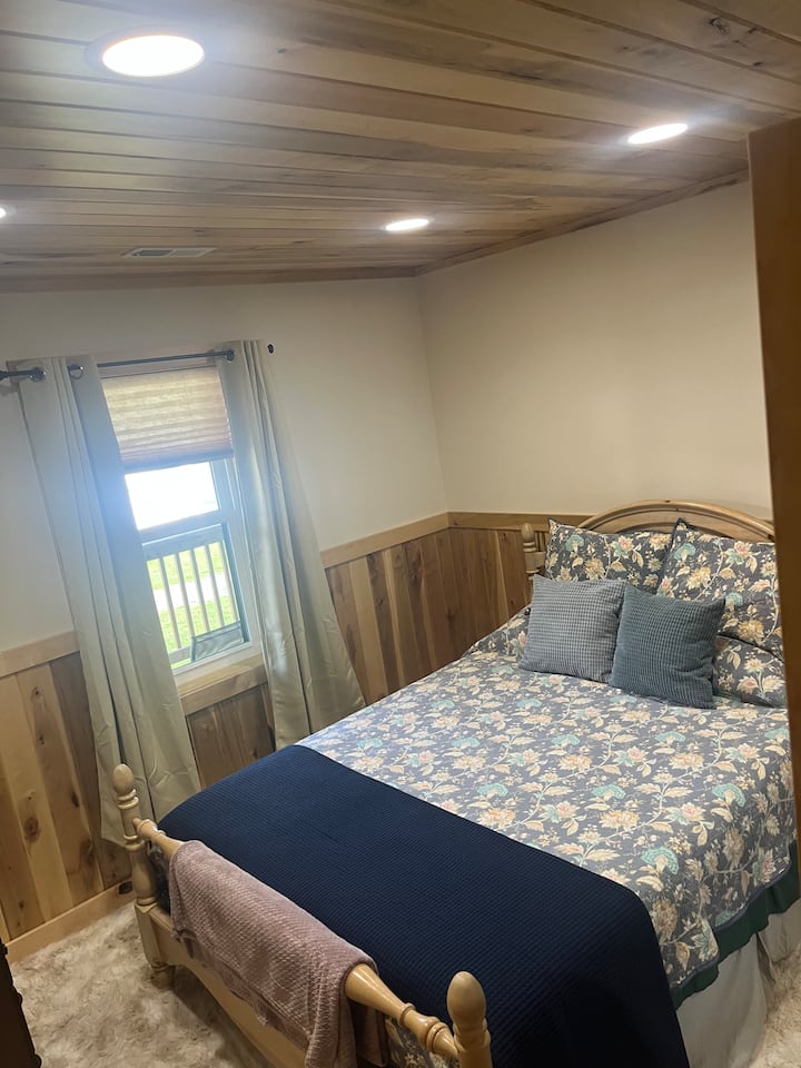 Primer dormitorio con cama tamaño queen y mantas adicionales en el armario.