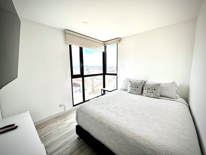 Moderná izba s manželskou posteľou a veľkým oknom, ktoré prepúšťa prirodzené svetlo. Útulný priestor na oddych a užívanie si pobytu.