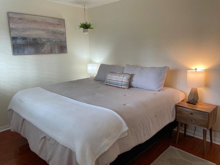 Cama tamaño king, dos mesitas de noche, TV, armario con cómoda en el interior. 