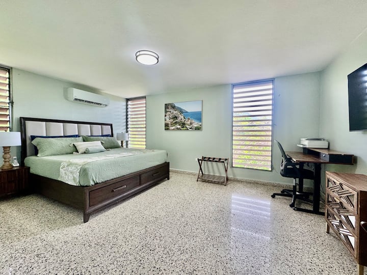 Priestranná a dobre vyvážená hlavná spálňa s manželskou posteľou veľkosti King, 65-palcovou inteligentnou televíziou a funkčným pracovným priestorom s počítačovým stolom a tlačiarňou