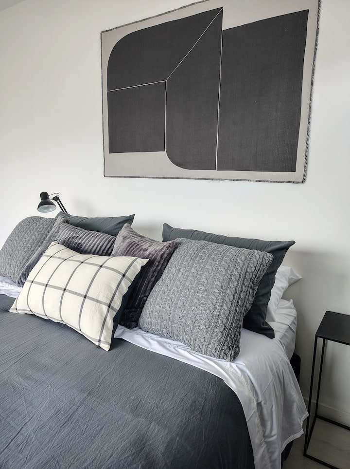 Cama queen con doble almohada y almohadones.