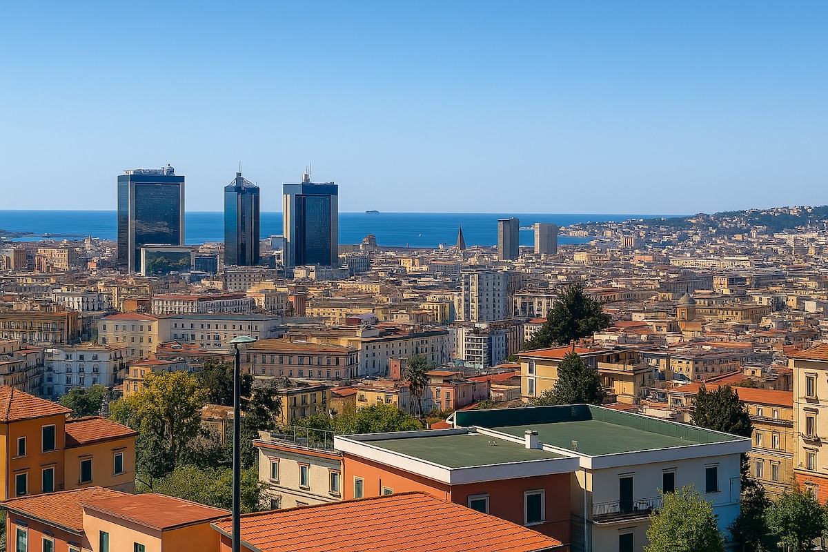 A panoramic view captures the vibrant cityscape of Naples, featuring modern skyscrapers against the backdrop of the blue sea. The image includes a variety of urban buildings with distinctive architectural styles and terracotta rooftops, set under a clear blue sky.