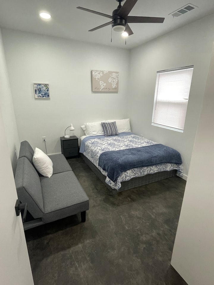 Удобна спална соба 2 со брачен кревет, сина постелнина и перници. Вклучува тавански вентилатор со светло, отворен плакар и ноќна масичка со ламба. Футонот додава опција за единечен кревет. Се одликува со бетонски подови. Одлично за удобен престој!