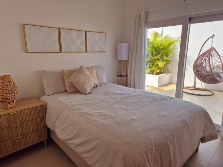 Оваа спална соба има удобен брачен кревет (широк 150-179 см) со неутрална постелнина, дрвена ноќна масичка со ткаена ламба и едноставна ѕидна уметност. Се отвора кон приватен поплочен двор со бујни растенија и висечки плетен стол. Собата има и сопствена бања и 40-инчен телевизор.