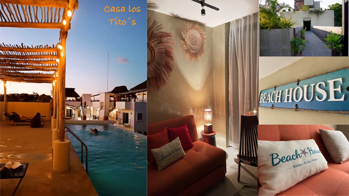 A tranquil pool area is framed by wooden structures, with gentle lighting illuminating the space as dusk approaches. A pathway leads through well-maintained landscaping, while a cozy lounge area features a soft couch, decorative pillows, and warm lighting, creating a welcoming ambiance.