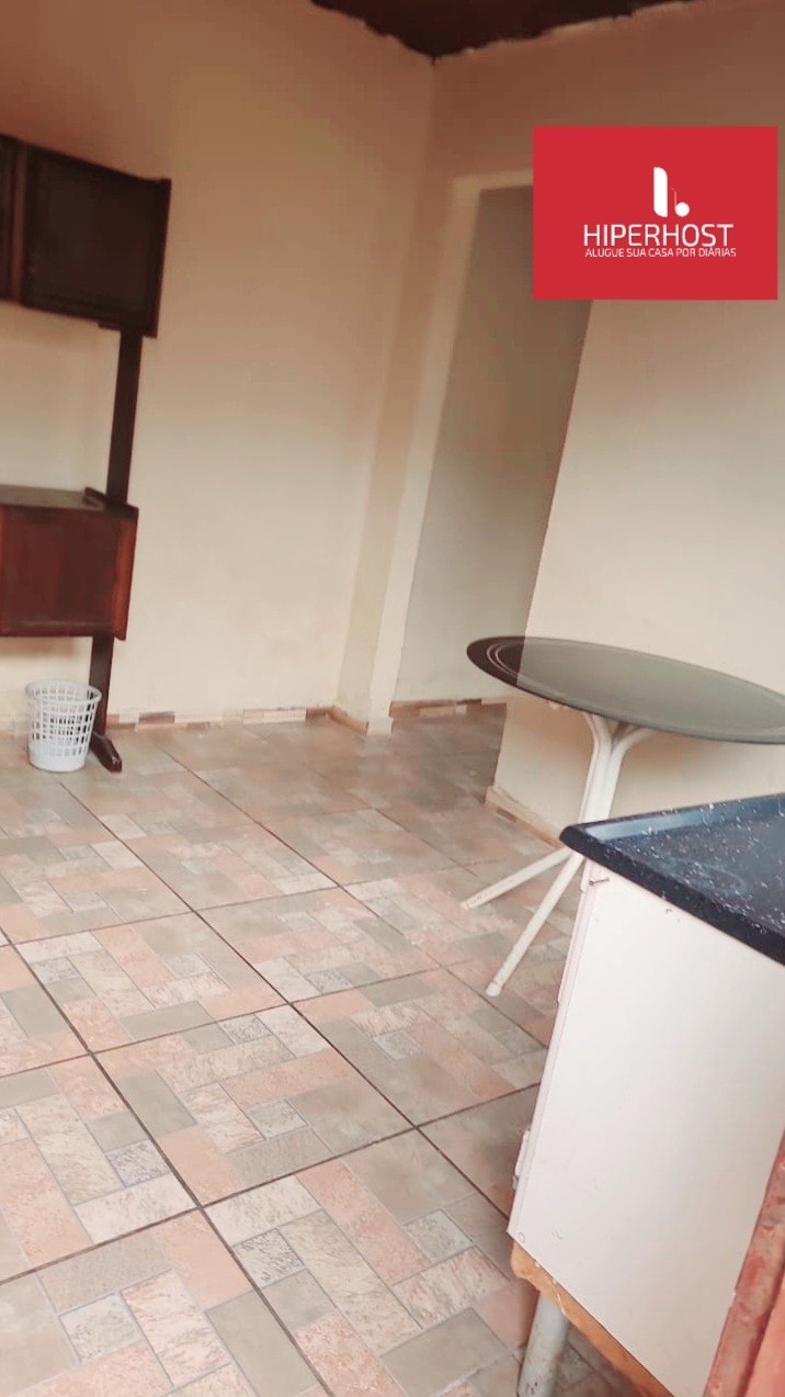 A clean kitchen space is shown, featuring tiled flooring and neutral walls. A round table is positioned adjacent to a cupboard, providing ample area for meal preparation. A basket is placed nearby, adding a functional element to the layout.