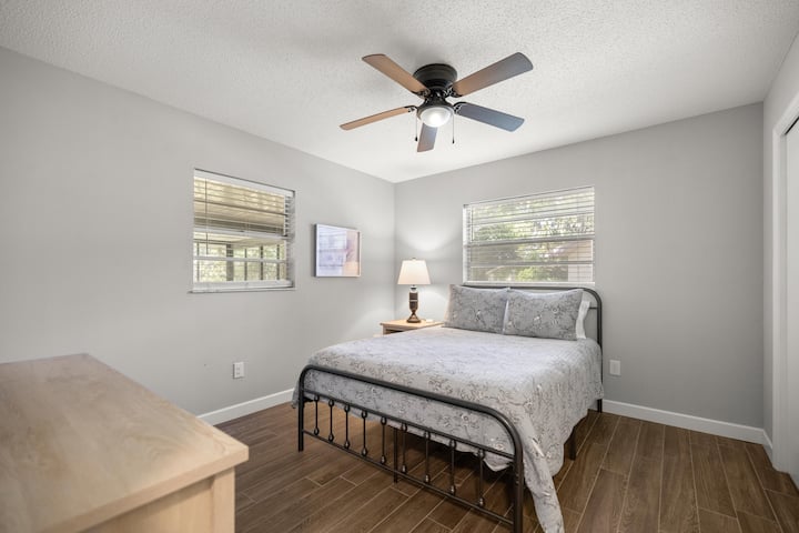 Chumba hiki cha kulala kinachovutia kinatoa faragha tulivu na kuta zake laini za kijivu, na mwanga wa asili unaotiririka kupitia madirisha mawili na kitanda kizuri kilicho na fremu ya chuma cheusi maridadi.