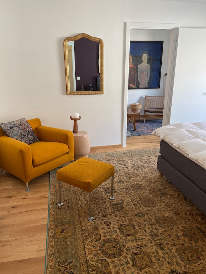 Chambre spacieuse avec un charmant mélange de confort et de caractère – un lit boxspring, une armoire ancienne et un fauteuil de lecture confortable créent une atmosphère chaleureuse. L'accès direct au balcon apporte de la lumière et de l'air dans la chambre.