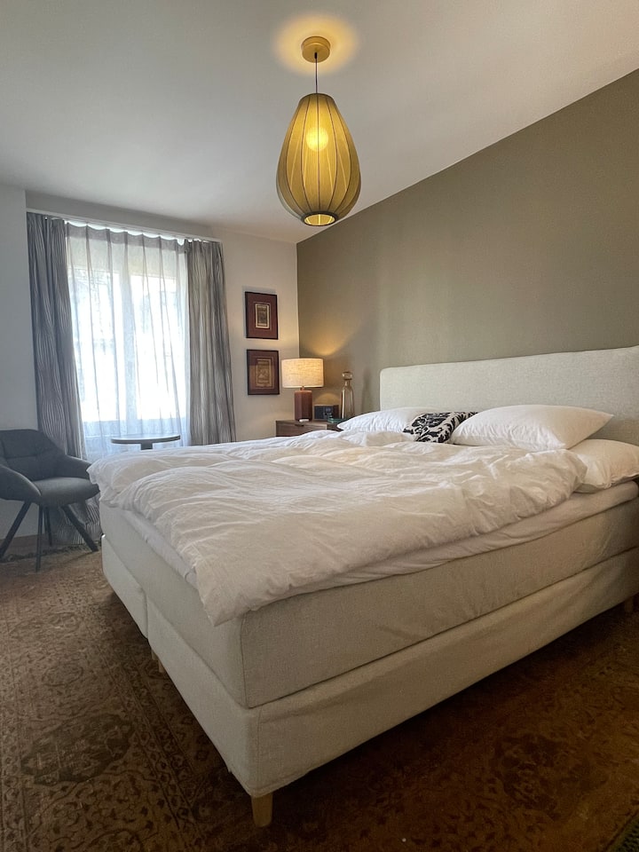 Chambre avec facteur de bien-être – se réveiller le matin et mettre les pieds sur un tapis de soie doux. Un lit boxspring de 180 cm de large, des fauteuils confortables, des lampes de chevet dimmables et un espace de rangement suffisant pour le confort et le style.