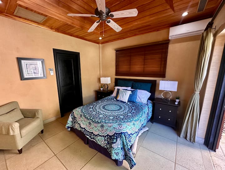 Dormitorio en la planta alta #2 con cama tamaño queen, balcón, ventilador de techo, aire acondicionado dividido y baño privado en el jardín. 