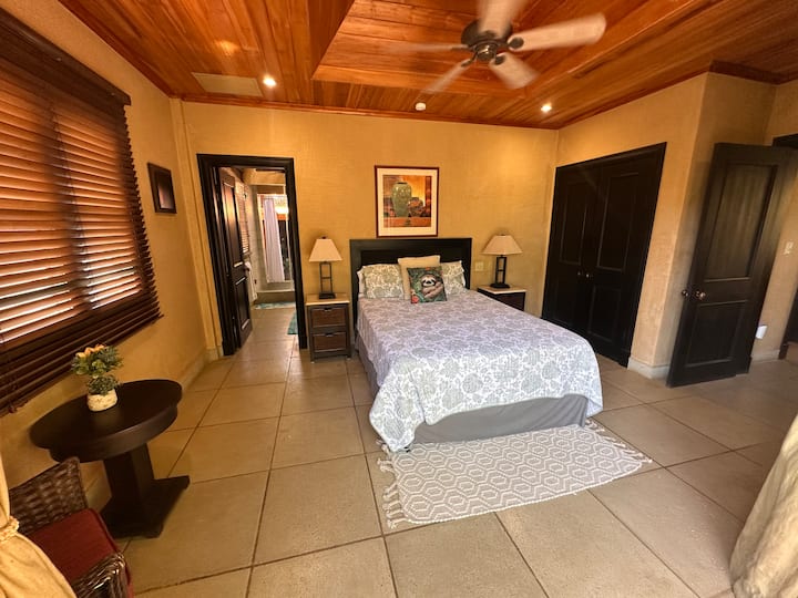 Dormitorio #1 en la planta alta con cama tamaño queen, balcón, ventilador de techo, aire acondicionado central y baño privado en el jardín.