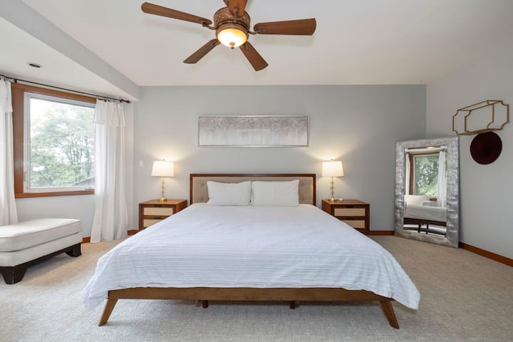 เตียงคิงไซส์ทรงเตี้ยใหม่เอี่ยมพร้อมผ้าปูที่นอนผ้าฝ้ายสำหรับเดือนที่อากาศอบอุ่น และผ้าฟลานเนลเมื่ออากาศหนาวเย็นโต๊ะข้างเตียงแต่ละตัวมีลิ้นชักเก็บของ 2 ลิ้นชัก