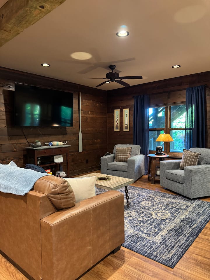 Всекидневната на по - ниско ниво предлага удобно и универсално пространство с диван за спане за допълнителни гости и два въртящи се стола за спокойни места за сядане. Нов голям телевизор го прави идеален за филмови вечери или излежаване след ден край езерото.