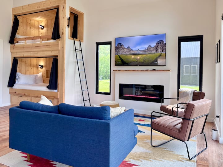 Dnevni boravak u smještaju River's Edge sa smart TV-om, električnim kaminom i krevetima na kat s dva ležaja veličine XL.