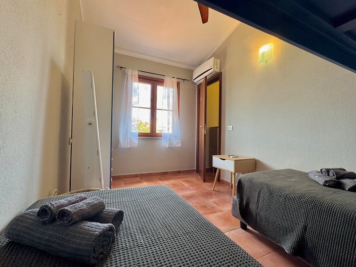 Chumba kinachofanya kazi na chenye mwanga, chenye vitanda vya mtu mmoja, kitanda cha ghorofa cha robo tatu, kabati kubwa la nguo na kiyoyozi kwa starehe ya juu.