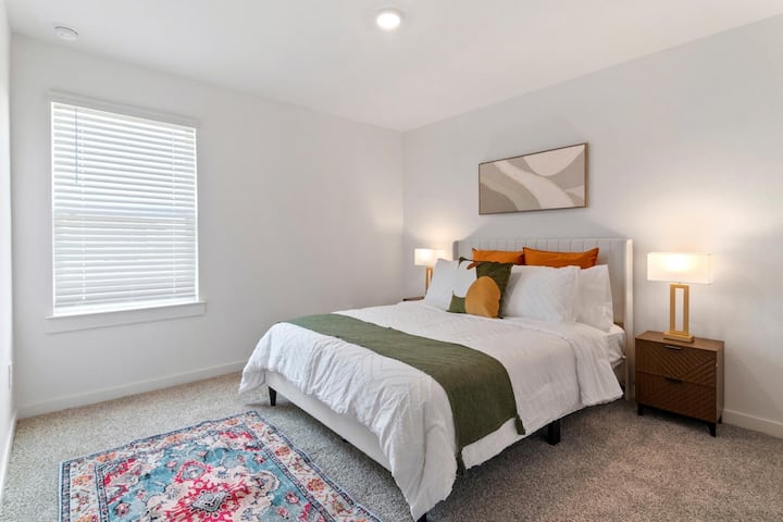 Habitación luminosa y cómoda con una cama tamaño queen con sábanas limpias, almohadas decorativas y alfombras suaves.
