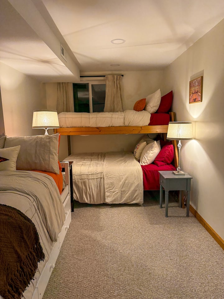 Habitación con literas con escritorio de trabajo, litera con cama de matrimonio en la parte inferior y cama individual en la parte superior