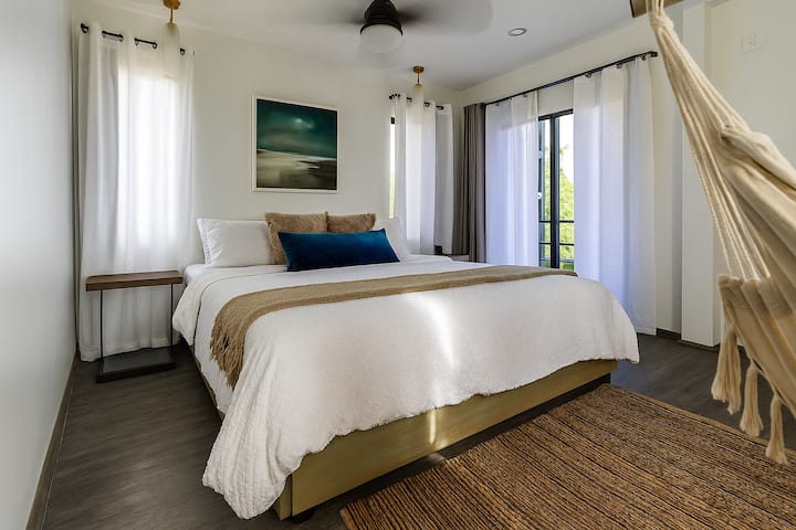 A moody, cocoon-like bedroom designed to help you rest and recharge, complete with a minimalist clothing rack and soft, ambient lighting—where mornings feel still, slow and deeply grounding.