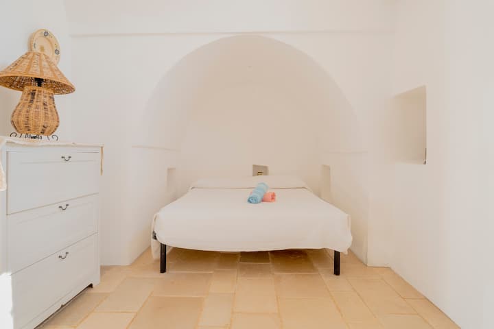Luminosa camera da letto matrimoniale con pavimento in pietra locale, biancheria da letto confortevole e caratteristiche persiane blu