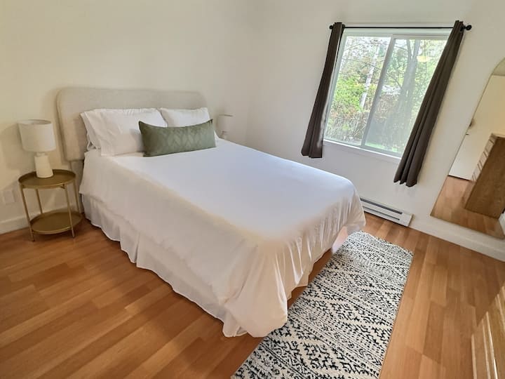 Spacious master bedroom with queen size bed, ensuite bathroom, large double-sided closet, dresser and full-length mirror.