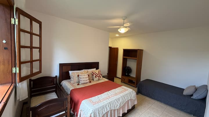 Dormitorio con cama tamaño queen, cuna, TV, ventilador y cortina opaca