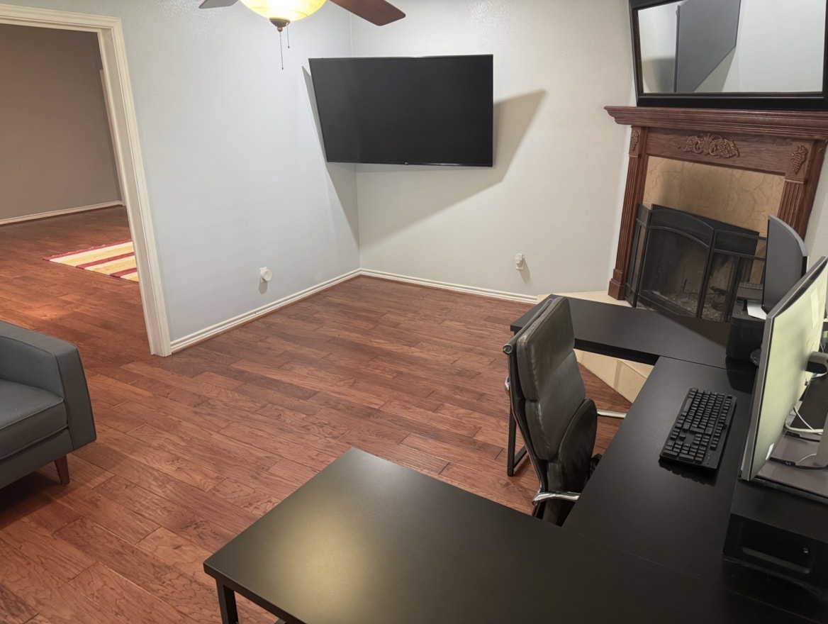 Bonus gaming and work room with a wall-mounted TV, desk, and ergonomic gaming chair.