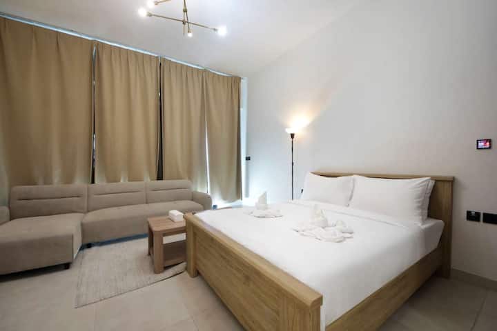 Pasa tiempo en el área del dormitorio, donde una cama cuidadosamente preparada y mesitas de noche definen un lugar de descanso dentro del estudio. La luz natural y un diseño equilibrado apoyan las noches tranquilas y una buena noche de descanso después de su día en Dubai.